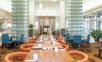 a large dining room with wooden tables and chairs arranged for a group of people at Hilton Garden Inn Wooster
