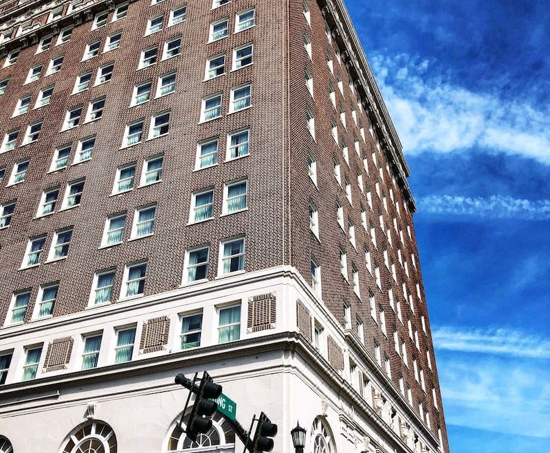 a tall building with a red brick facade and many windows is next to a street lamp at Francis Marion Hotel