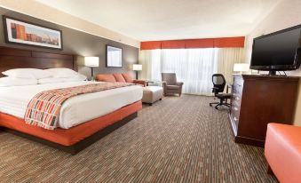 a modern hotel room with a large bed , two chairs , and a desk , all arranged in a comfortable and well - organized layout at Drury Inn & Suites St. Louis Airport