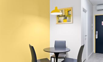 a dining area with two chairs and a small round table in front of a yellow wall at ValueSuites Green Square