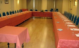 a large conference room with multiple long tables set up for a meeting , each table having its own set of red tablecloths at La Cañada