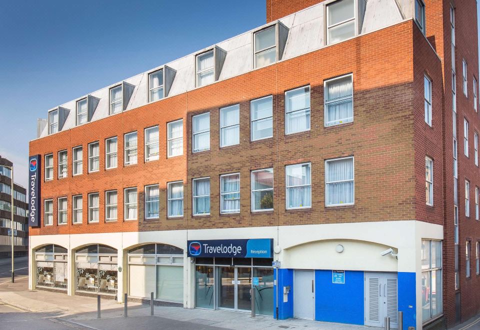 a brick building with multiple windows , located on a city street under a clear blue sky at Travelodge Norwich Central Riverside