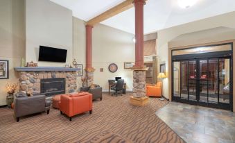 a spacious living room with an orange couch , brick columns , and a large screen tv at AmericInn by Wyndham Rogers