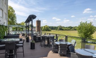 a wooden deck overlooking a grassy field , with several tables and chairs set up for outdoor dining at The Mill Hotel