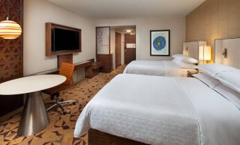 a modern hotel room with two beds , a desk , and a flat - screen tv , along with some personal items on the desk at Sheraton Grand Seattle