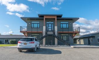 a modern , two - story house with a car parked in the driveway and stairs leading up to it at Colony Suites