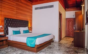 a hotel room with a wooden floor , a bed with blue sheets , and a door leading to another room at Aquays Hotels & Resorts