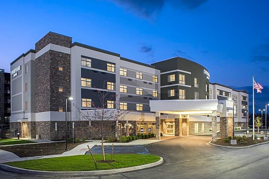 a modern hotel building with a black and white color scheme , surrounded by trees and parked cars at Courtyard Schenectady at Mohawk Harbor