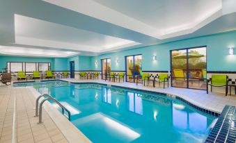 an indoor swimming pool surrounded by lounge chairs , with people enjoying their time in the pool area at SpringHill Suites Cleveland Solon