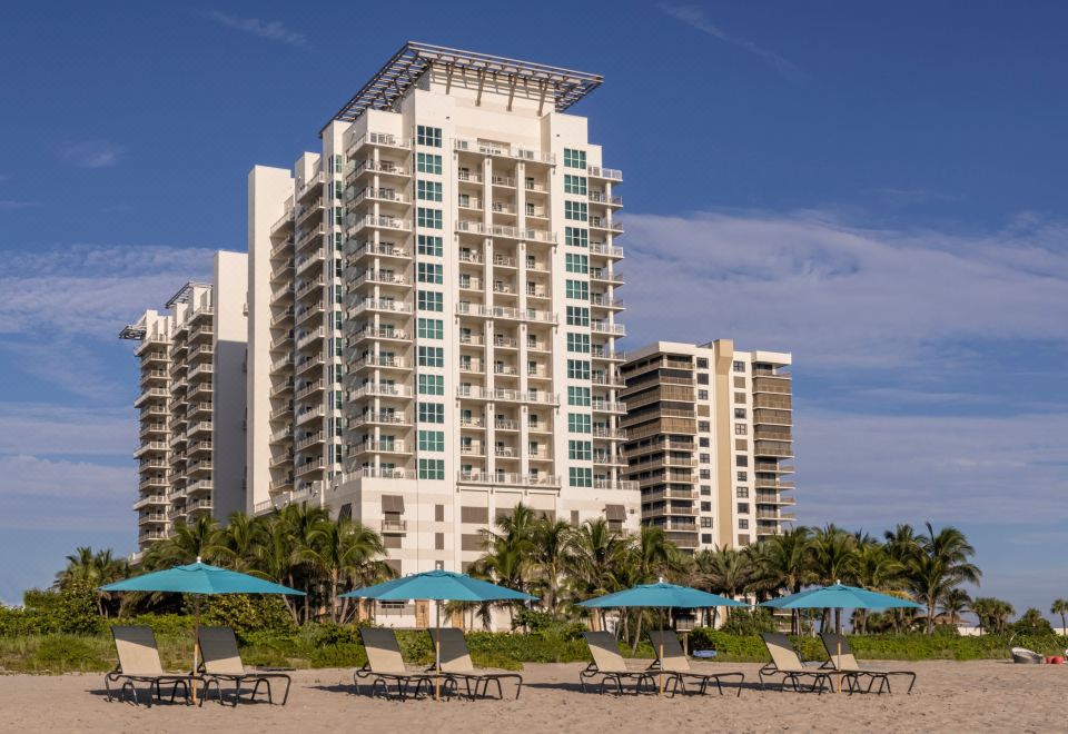 a modern apartment building with many balconies and blue umbrellas on the beach , under a clear sky at Marriott's Oceana Palms