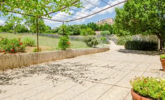 a paved walkway surrounded by lush green grass , with a pond in the background , creating a serene and picturesque scene at Les Cotes