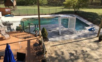 a backyard with a swimming pool surrounded by a wooden deck , and a dining table nearby at Oak Creek Lodge