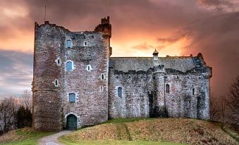 a medieval castle with stone walls and towers , set against a backdrop of a cloudy sky at sunset at The Forth Inn