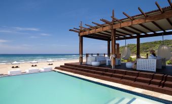 a beautiful outdoor pool area with a wooden pergola , surrounded by blue sky and clear water , under a clear blue sky at White Pearl Resorts