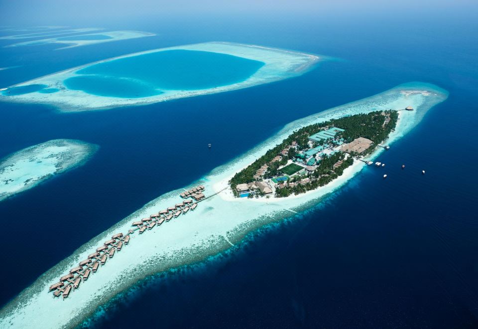 aerial view of a large tropical island surrounded by clear blue water , with a resort visible on the island at Vilamendhoo Island Resort & Spa
