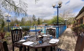 a wooden table with plates and silverware is set up in an outdoor area near a pool at Novotel Manchester West