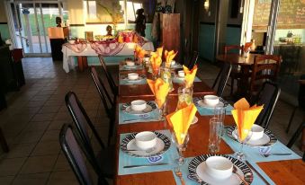 a long dining table set for a meal , with multiple plates and cups placed on the table at Umkomaas Lodge