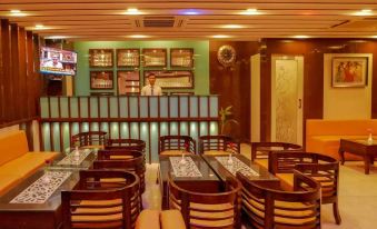 a restaurant with wooden tables and chairs , a television on the wall , and framed pictures on the wall at Emporio Hotel
