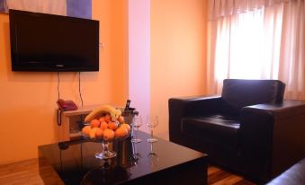 a living room with a black leather couch , a glass of wine , and a television at Alfa Hotel