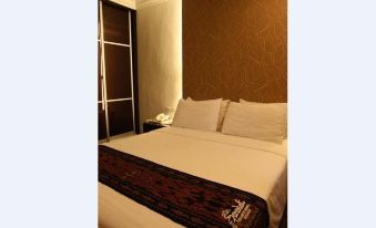 a large bed with white sheets and a brown blanket is in a room with a brown wall at Royal Hotel