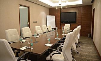 a conference room with a wooden table , white chairs , and a tv mounted on the wall at Hyatt Centric Janakpuri New Delhi