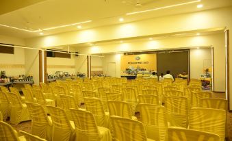 a large conference room with rows of yellow chairs arranged in a semicircle , and a stage set up for an event at Hotel Center Point