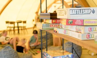 "a bookshelf filled with various board games , including board games titled "" battlehouse "" and "" rise and shine ""." at Under Canvas Mount Rushmore