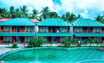 a tropical resort with multiple buildings , a swimming pool , and lush greenery under a cloudy sky at Aquays Hotels & Resorts