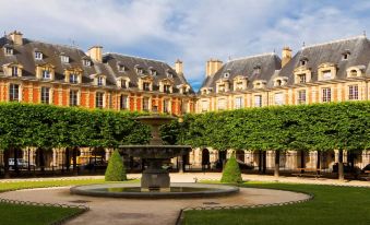 a courtyard with a fountain surrounded by a building , creating a serene and picturesque setting at Ibis Styles Paris Mairie de Montreuil