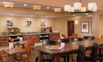 a large dining room with a long wooden table , multiple chairs , and a kitchen in the background at DoubleTree by Hilton Portland - Tigard