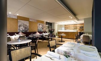 a restaurant with white tablecloths and chairs , featuring a large glass display case in the background at Residence Hotel