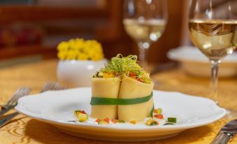 a white plate with a small dish of food on it , next to a wine glass at Miravalle