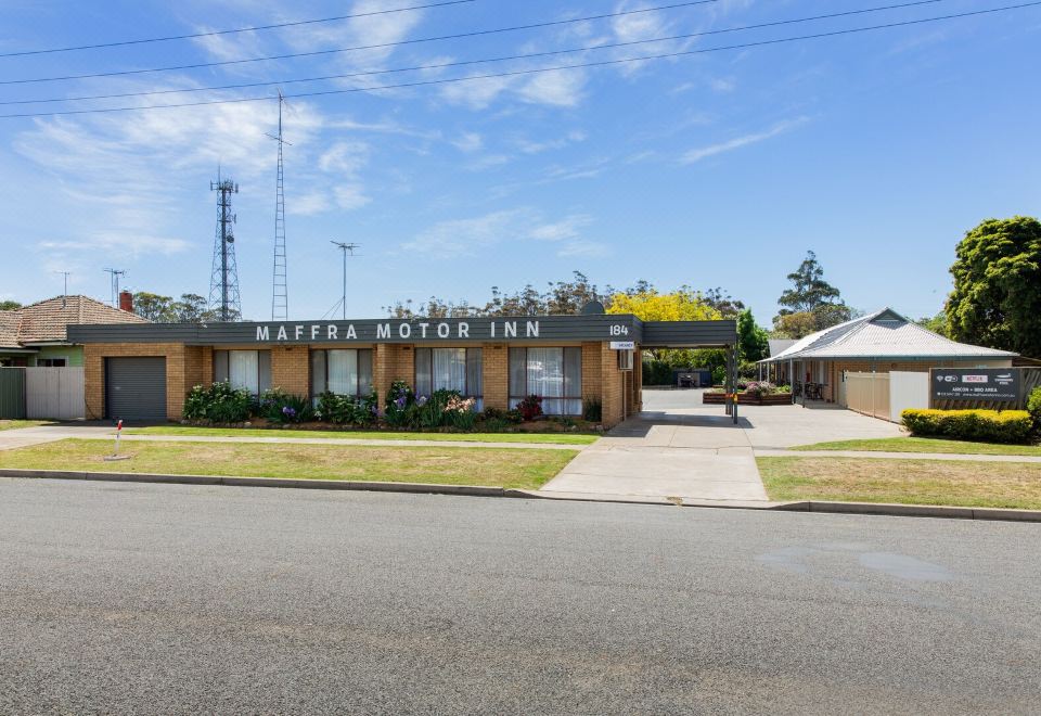 "a large building with a sign that says "" mayra motor inn "" is surrounded by trees and grass" at Maffra Motor Inn