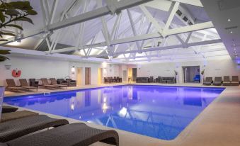 an indoor swimming pool with a white ceiling , surrounded by lounge chairs and a ceiling with exposed beams at The Telford Hotel, Spa & Golf Resort