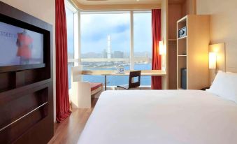 A bedroom with a double bed and a large window that overlooks the city from one side at ibis Hong Kong Central and Sheung Wan Hotel