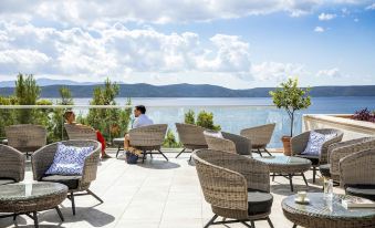 a man and a woman sitting at a table on a patio overlooking a body of water at Tui Blue Makarska