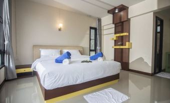 a large bed with white sheets and blue pillows is in a room with a wooden headboard at Phuphayot Resort