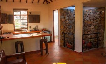 a kitchen with a table , chairs , and a sink is shown next to a hallway with a stone wall at Casa Bohemia