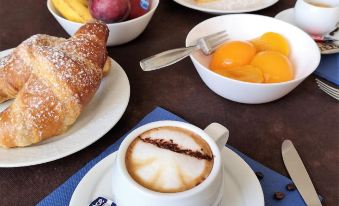 a dining table with a variety of food items , including croissants , fruit , and a cup of coffee at Hotel Panorama