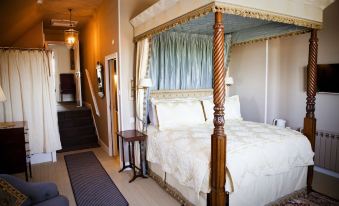 a large bed with a wooden canopy and white linens is in a room with a blue and gold canopy at The Carden Arms
