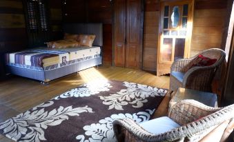 a bedroom with a large bed , a chair , and a rug on the floor in front of a window at Rock and Wreck Dive Resort