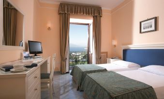 a hotel room with two beds , a desk , and a window overlooking a beautiful view at Hotel Jaccarino