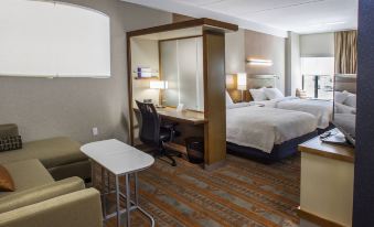 a modern hotel room with a bed , desk , chair , and couch , as well as a tv on the wall at SpringHill Suites Deadwood