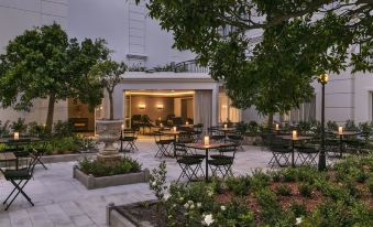 a courtyard with several tables and chairs set up for outdoor dining , surrounded by trees and plants at InterContinental Sydney Double Bay