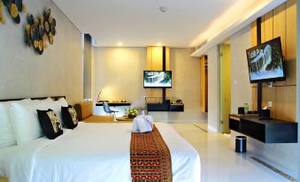 a large bed with a red and white blanket is in a room with a television at BBC Hotel Lampung Bandar Jaya