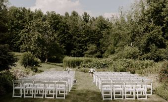 an outdoor wedding ceremony with rows of white chairs set up in a grassy field at Windham Hill Inn