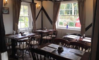 a large room with wooden tables and chairs , and a window overlooking a garden filled with red poppies at Sorrel Horse Inn