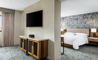 a hotel room with a king - sized bed , a flat - screen tv mounted on the wall , and a dresser at Sheraton Philadelphia Downtown