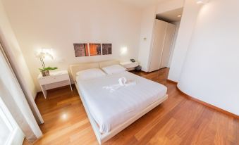 a large white bed with a white comforter is in the middle of a room with wooden floors and two nightstands at La Castellana