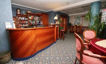 a hotel lobby with a wooden reception desk , multiple chairs , and a bookshelf filled with books at Waterfront